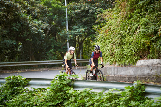 two young asian female cyclists riding road bikes in the countryside
