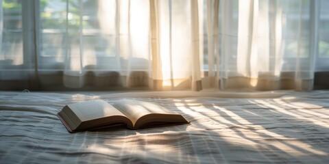 An open book placed on a bed in front of a window, letting in sunlight, creating a cozy reading spot