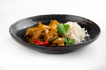 Juicy pieces of chicken with curry sauce and white rice on a plate on a white background