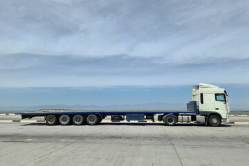 Side view of a large length cargo big truck with copy space on a blue sky.