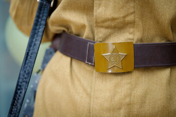 A soldier's buckle with the emblem of a star, hammer and sickle, worn in honor of the Great Victory Day on May 9, close up.