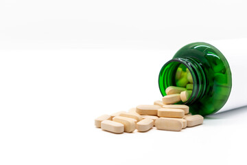 Yellow pills coming out of a green plastic bottle with blank label. Copy space. Medicine and health concept. selective focus