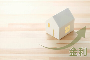 住宅ローン金利上昇のイメージのコラージュ写真。ミニチュア模型の家。