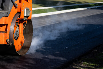 Closeup of steamroller compacting freshly load asphalt, residential road repaving construction...