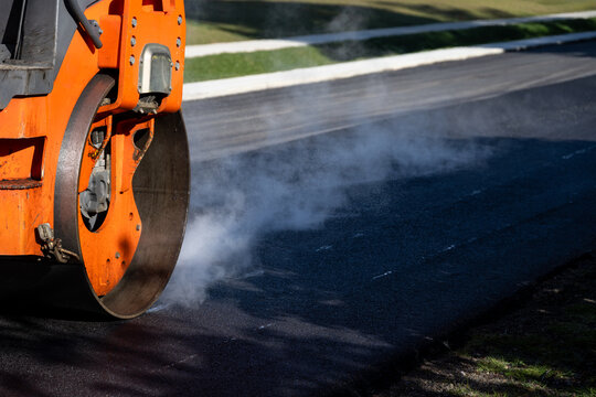 Closeup of steamroller compacting freshly load asphalt, residential road repaving construction project
