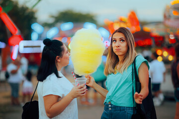Girls Having Fun Having Cotton Candy and Juice at a Festival. Friends attending a funfair together...