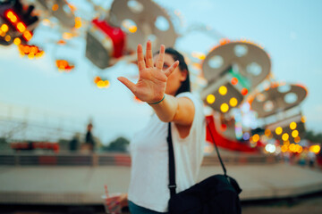 Girl Making Stop Gesture with her Palm at a Funfair. Unhappy woman making a halt signal pushing...