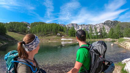 Hiker couple at alpine lake with scenic view of mountain peaks Feistritzer Spitze (Hochpetzen) and...