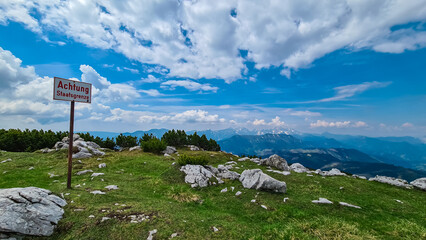 Sign indicating top of mountain peak Kriznik, Carinthia, border Austria Slovenia. Alpine meadow with scenic view of mountain range Karawanks, Slovenian Austrian Alps. Hiking trail on Petzen, Bleiburg