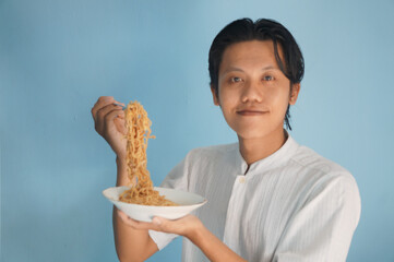 Portrait of happy young Asian man enjoying eating noodles. Lunch concept.
