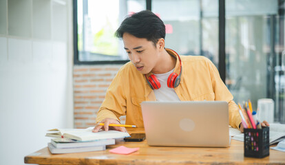 Young Asian college student working and learning on laptop In the cafe. Searching for knowledge...