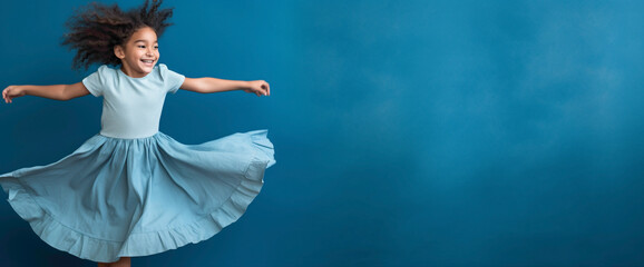 Little Girl Twirling with Joy Against a Solid Blue Wall Background.