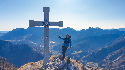 Happy hiker man at summit cross on top of mount Hochblaser in Eisenerz, Ennstal Alps, Styria,...