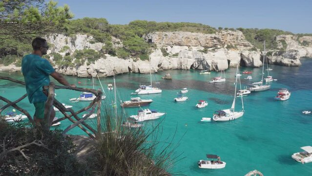 Man enjoys the spectacular view of the Cala Macarella in Menorca Island Spain
