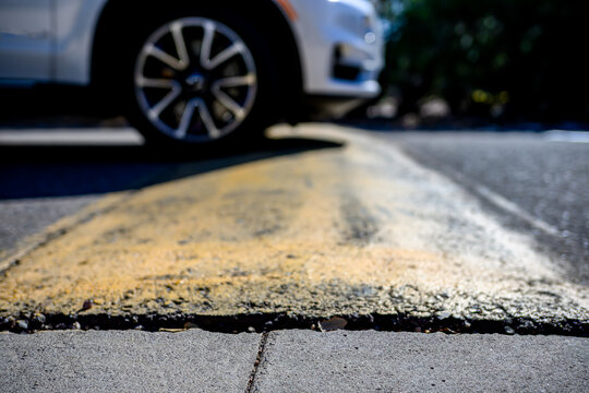 Selective focus on area in front of a speed bump with a car driving over.