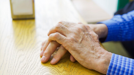 Hands of an elderly male cafe customer at a table waiting