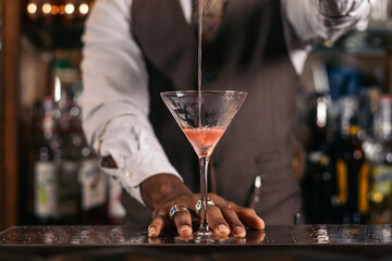 Black bartender preparing a cocktail in a traditional cocktail bar