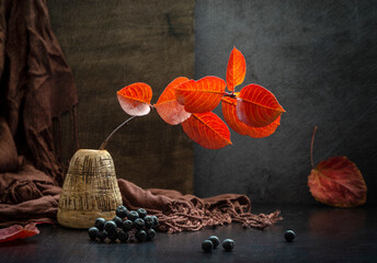 Modern still life with an autumn branch in a clay vase on a dark background