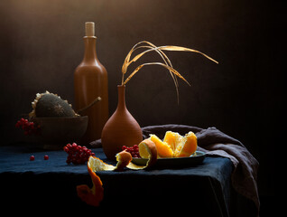 Modern still life with tangerine and dry grass in a clay vase on a dark background