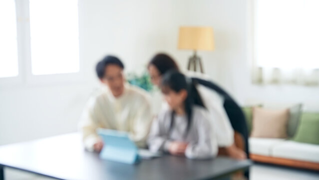 A family of an Asian girl and her parents looking at a tablet PC screen. Blurred concept.