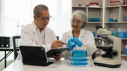 Two senior Asian men and women are scientists researching biology and chemistry. Couple wearing...