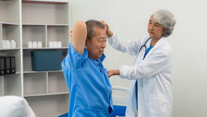  An old Asian man is doing physical therapy with the support of an elderly female nurse in the...