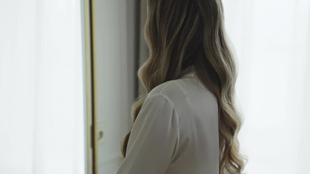 A woman with long hair is sitting in front of a mirror