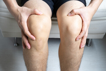 Man with knee pain, he puts his hand on his knee, pain point from osteoarthritis and...