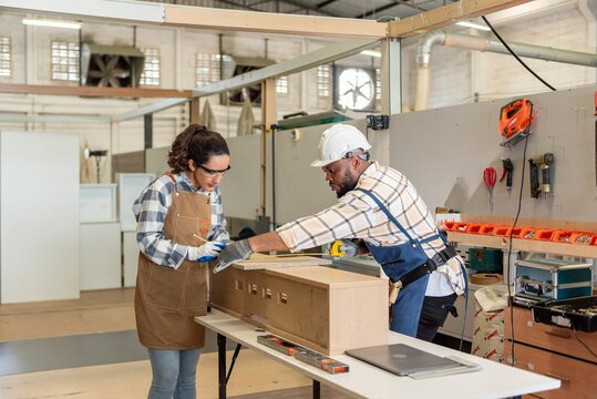 Two colleague young aged carpenter standing aim equipment tool for wood furniture at wood plank in workshop. coworker carpenter working craft with wood diy tool in workbench shop carpentry