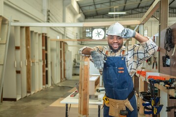 Carpenter man Portrait of Young black skin looking smile laugh to camera in workshop. Happy professional Carpenter holds wooden planks for build furniture in carpentry workshop. one carpenter worker