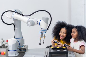 Kid female teen child enjoy Machine Learning Robot arm is Moving Under Control robot at technology...