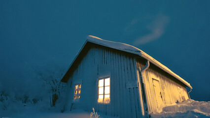 Fototapeta na wymiar A small cabin on a hill on a in the cold night sky covered with snow, Finland, Dec 2023