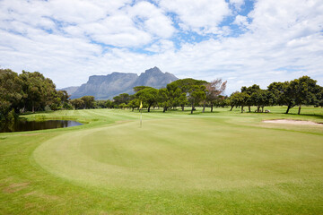 Grass, landscape and outdoor at golf course with mountain on luxury holiday or vacation. Calm, morning and lawn with turf for sport in woods, forest or nature of park with field and trees in summer