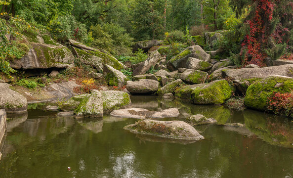 Large stones by the lake in the forest in Sofievka park in Uman