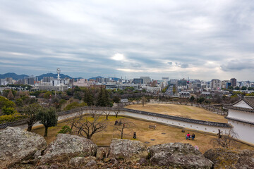 High angle view of famous Unesco Word Heritage site Himeji-jo castle over park and Japanese City of Himeji on a cloudy gray winter day. Photo taken February 1st, 2024, Himeji, Japan.