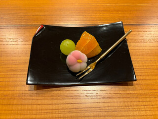 High angle view of Japanese dish at lunch time with dessert fruits on black plate on table of restaurant on a winter day. Photo taken February 5th, 2024, Kyoto, Japan.