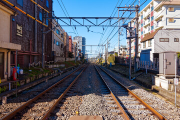 Diminishing perspective of railway tracks at Araiyakushi-mae Station at Japanese City of Tokyo with cityscape on a sunny winter day. Photo taken January 27th, 2024, Tokyo, Japan.