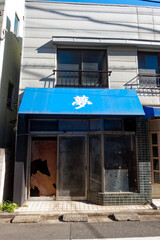 Wrecked former shop with white Japanese character dream on blue sunshade at Japanese City of Tokyo on a sunny winter day. Photo taken January 27th, 2024, Tokyo, Japan.