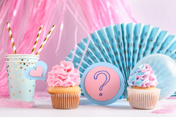 Delicious cupcakes with question mark and decorations on table against white background. Gender reveal party concept - obrazy, fototapety, plakaty