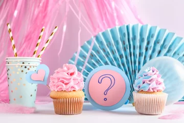 Poster Delicious cupcakes with question mark and decorations on table against white background. Gender reveal party concept © Pixel-Shot