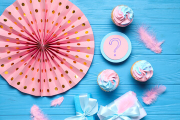 Delicious cupcakes with question mark, gift boxes and decorations on blue wooden background. Gender reveal party concept - obrazy, fototapety, plakaty
