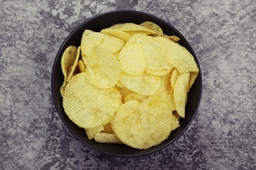 Potato Chips Snack in black bowl, close up photo top view