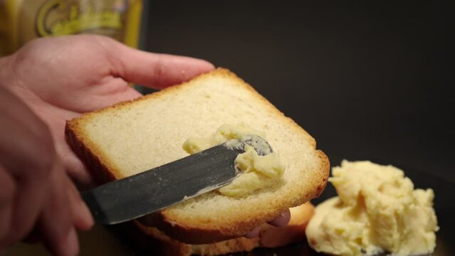 Butter cheese smooth soft creme peanut jelly putting on top of a toast of bread slice slow motion with black background female hands