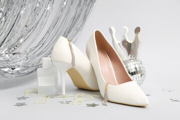 Paper crown with stylish high heels, disco ball, bottle of perfume  and tinsel on grey background....
