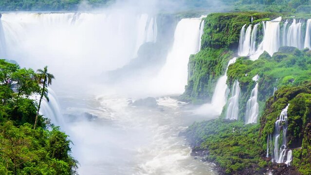 Timelapse of Waterfalls of Iguazu around a big green area and a river, in a sunny day, Foz do Iguacu, Parana, Brazil