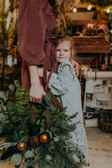 A girl hugging a woman holding a Christmas Wreath