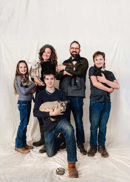 Farm family of five posing with their lambs.