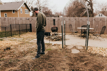 Man looks at strawberry patch while standing in backyard garden