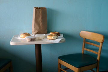 Table and chair with bagels against a blue wall
