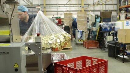 Worker carrying large bag of cap linings in an industrial factory setting, machinery visible